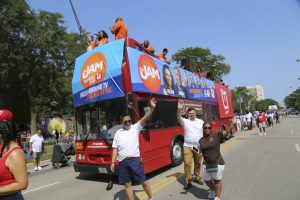 Ankin Law Office Participates in the Bud Billiken Parade 1 Ankin Law Office employees waving and smiling beside a big red bus at the Bud Billiken Parade