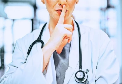 Doctor with her finger on her lips in a modern hospital.