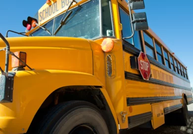 Yellow school bus with stop signage on the side.