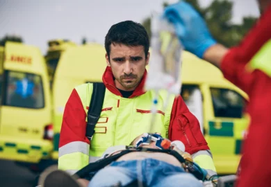 Emotional paramedic aiding a victim from a car collision.